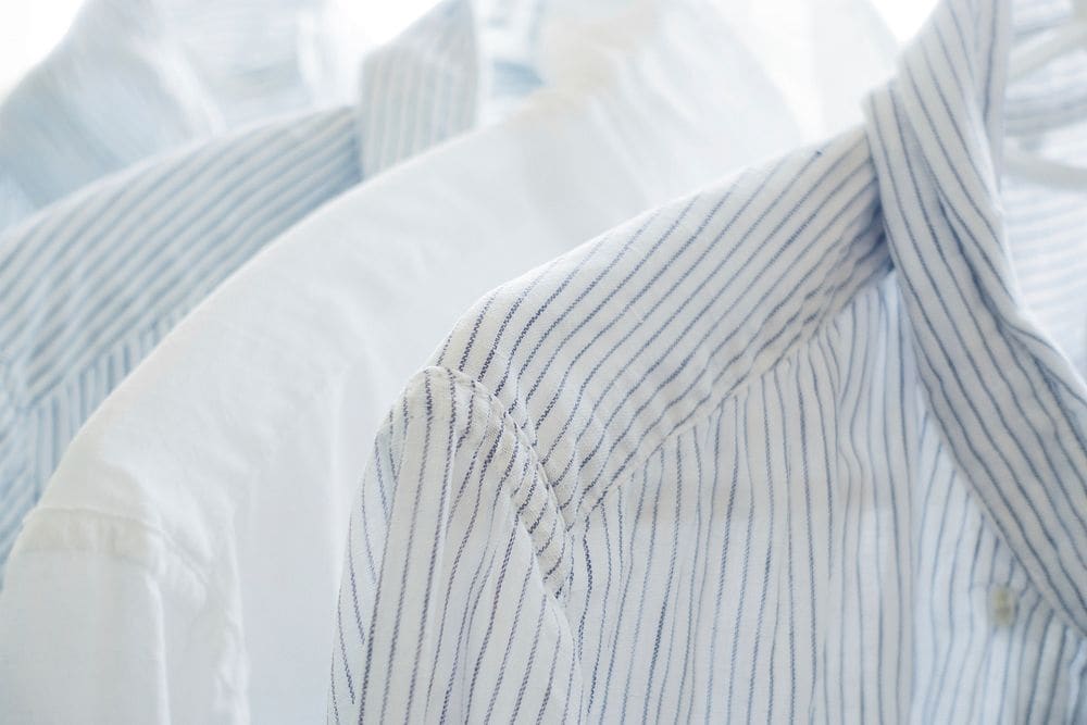 Close view of lightweight white and pinstriped cotton shirts hanging together.