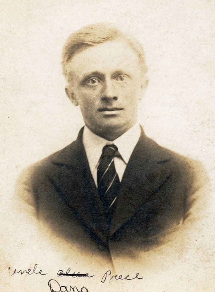 A sepia studio portrait of a young man in a dark suit, white shirt and narrow striped tie.